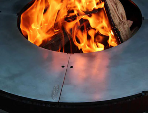 Fire burning in fire pit with a round centred Ringgrill BBQ Grill Plate