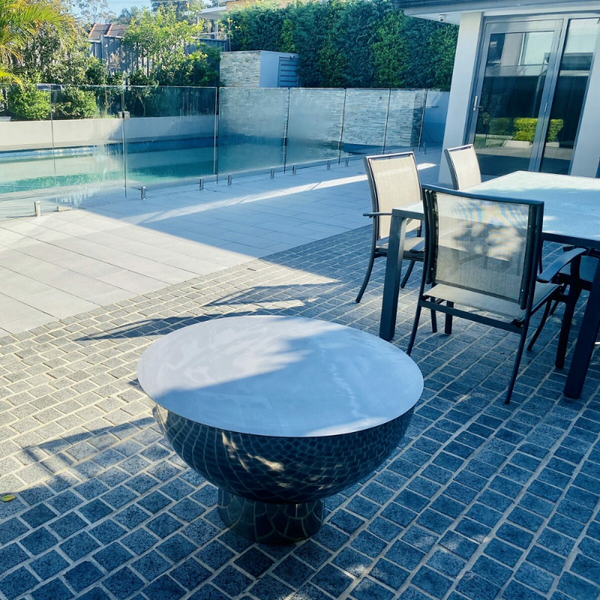 Stainless Steel Fire Pit Lid on the Goblet fire pit in a private patio setting beside a pool.