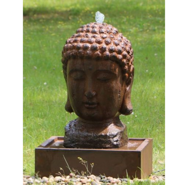Lucky Buddha Water Fountain with water flowing in garden in the day time, in a garden setting with pebbles, green grass and dandelions surrounding it.