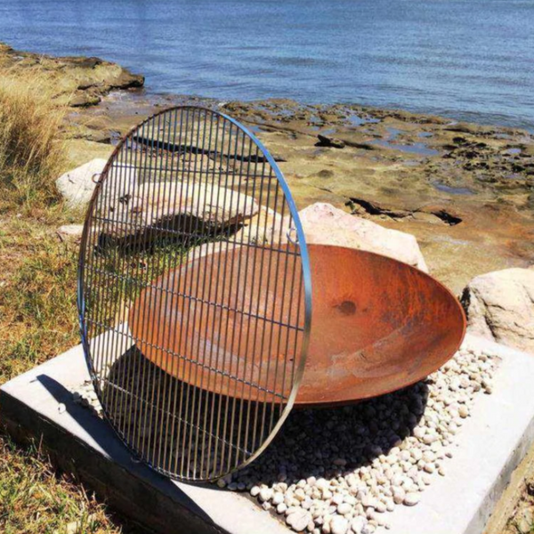 Stainless Steel BBQ Cooking Grill besides a fire pit at a rocky lakeside