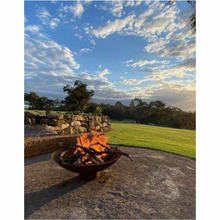 Load image into Gallery viewer, The Cauldron Fire Pit 1500mm burning a fire and half grill in background