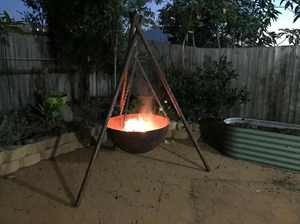 The Tripod Fire Pit in a backyard setting with fire burning