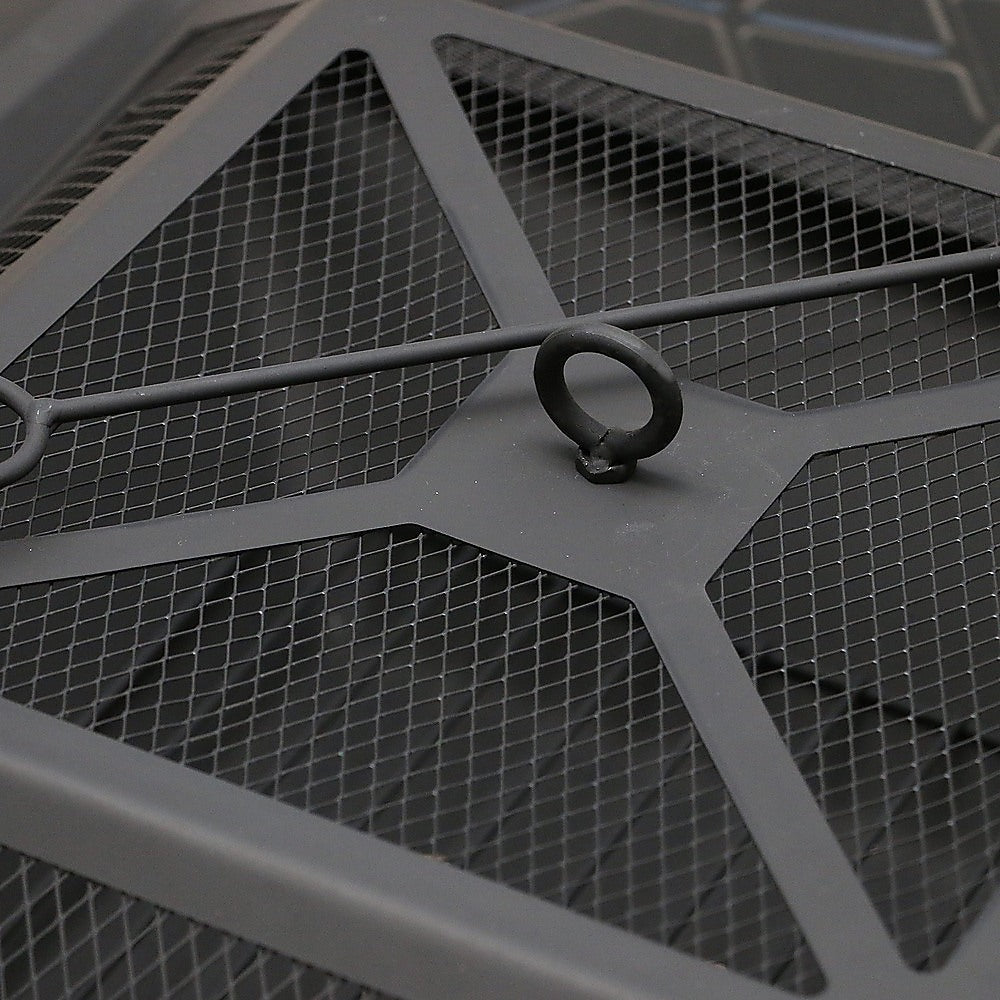Close-up image of the top of the mesh screen lid of a metal fire pit with poker laying across the top of it.