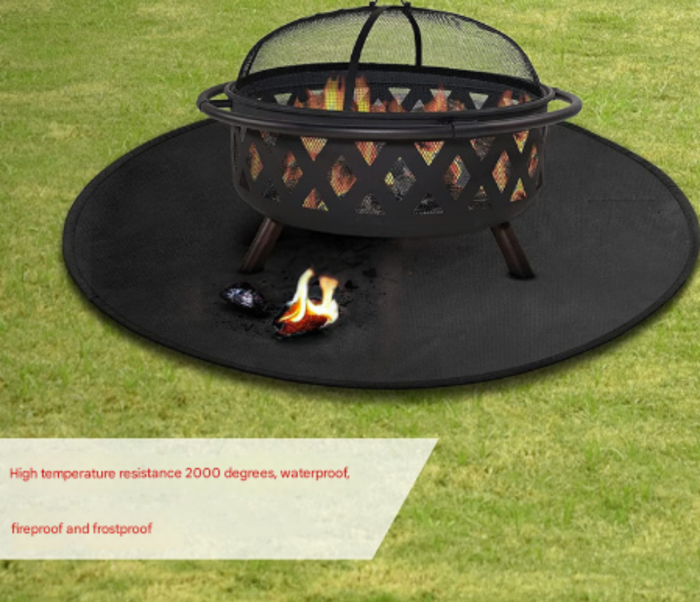 Fire pit with a fire on a black fire pit mat on grass, featuring text about fireproof properties.