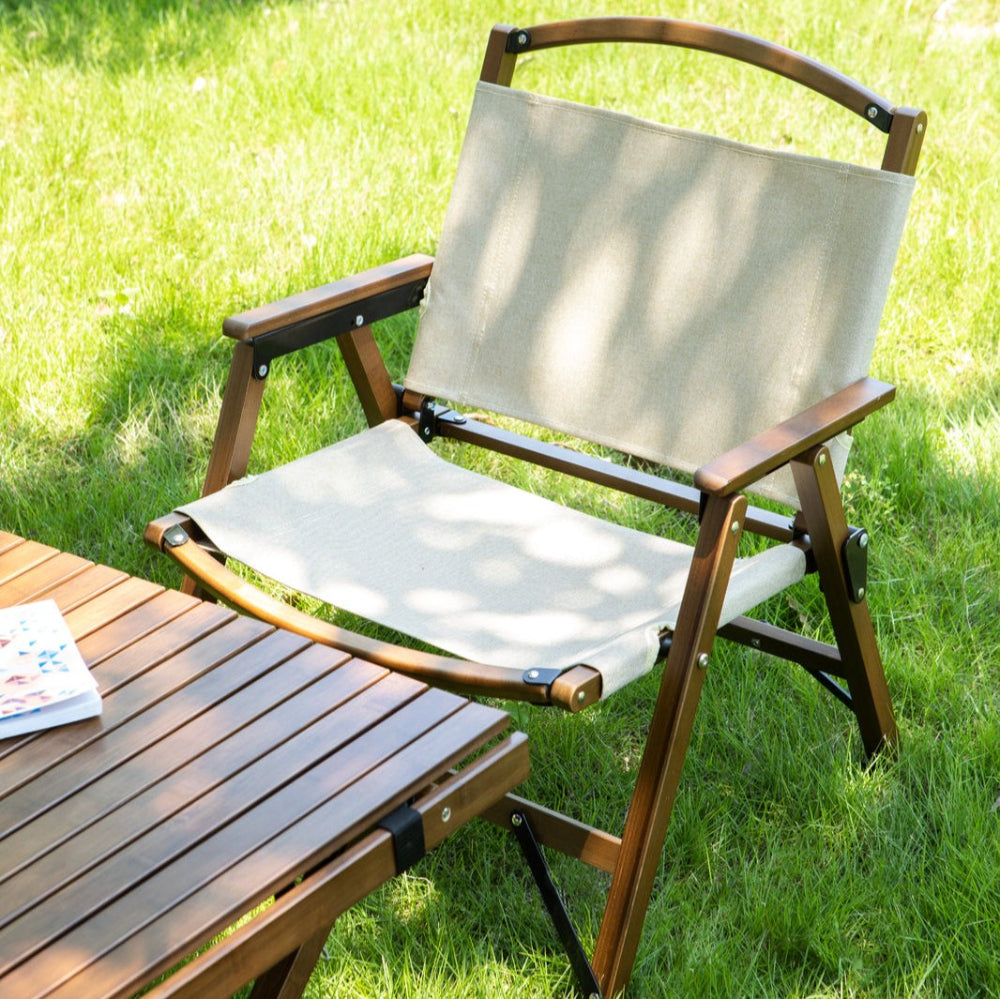 A foldable outdoor camping chair made of bamboo, with beige colored base and back, and a wooden frame on a grassy area.