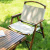 A foldable outdoor camping chair made of bamboo, with beige colored base and back, and a wooden frame on a grassy area.