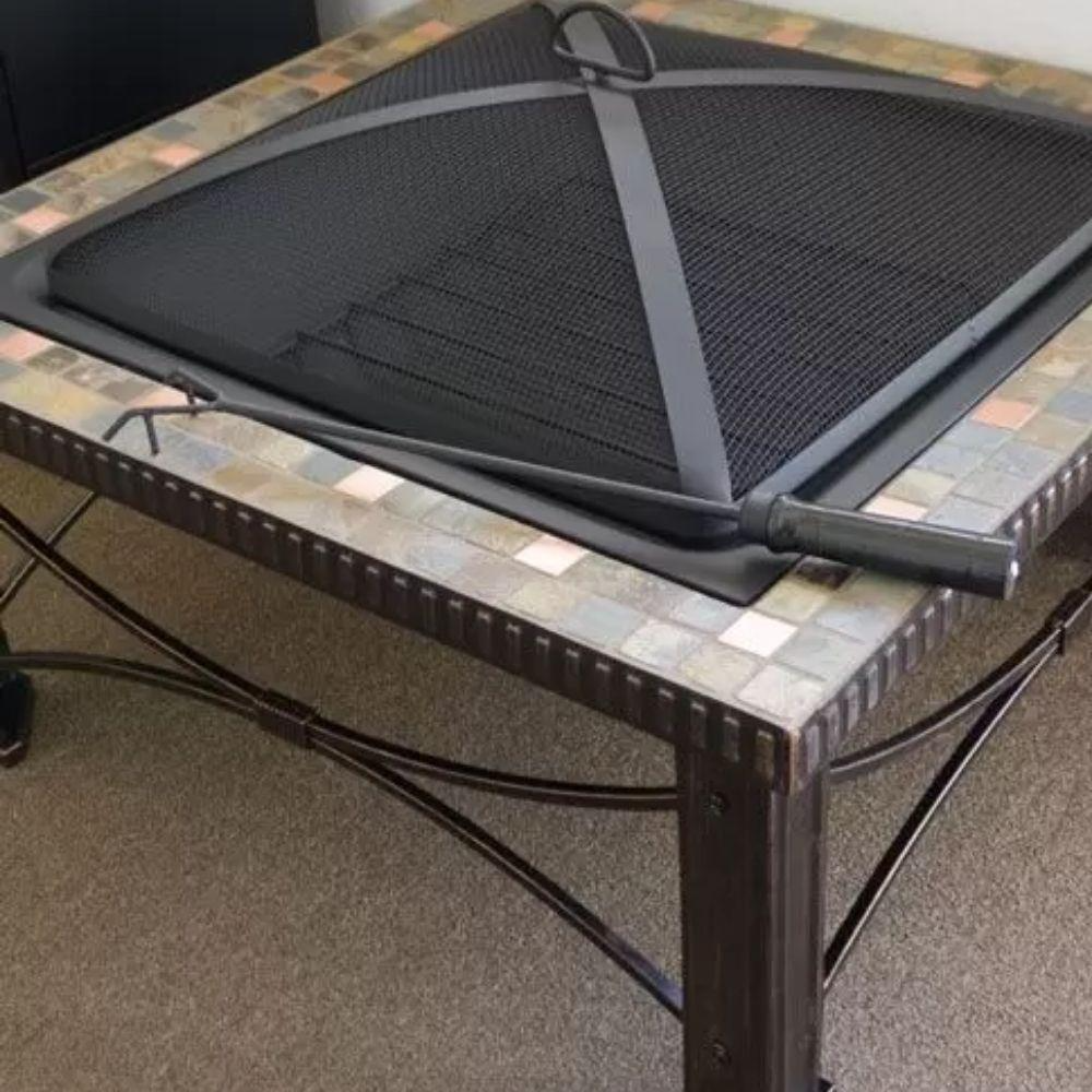 Black fire pit screen on a mosaic-tiled table