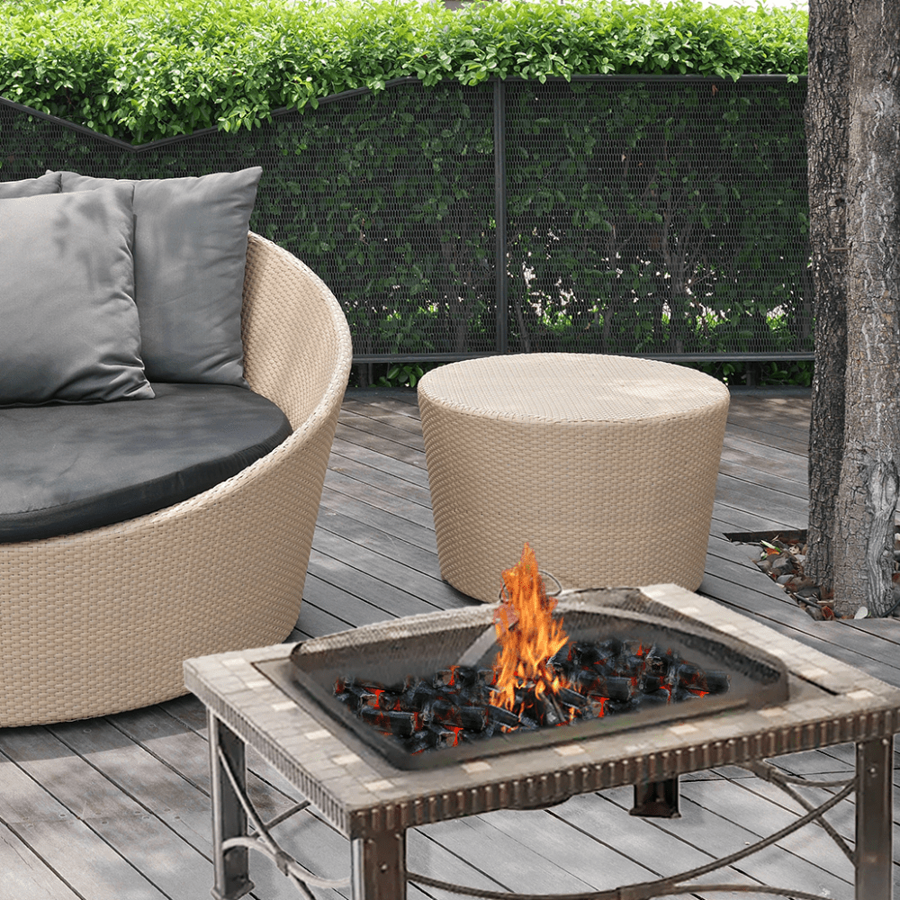 Outdoor patio setting with a fire pit table, round sofa, and ottoman on a wooden deck.