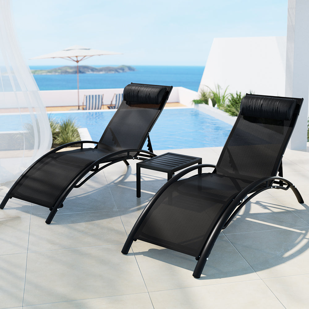 Two black Gardeon sun loungers with adjustable backrests and matching side table, set on large, tiled surface at a rooftop poolside overlooking an ocean view.