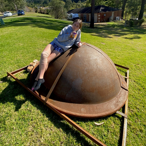 Young girl sitting on an upside down Crucible Fire Pit - Hot Fire Pits Australia