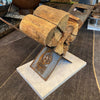 Wooden firewood stack on a metal stand with 'Unique Fire Pits' branding on a stone surface.