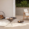 Outdoor patio setting with a chair, firepit, log rack and decorative items on a tiled floor.