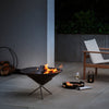 Outdoor patio with fire pit, chair, and wine glass on a dark evening.