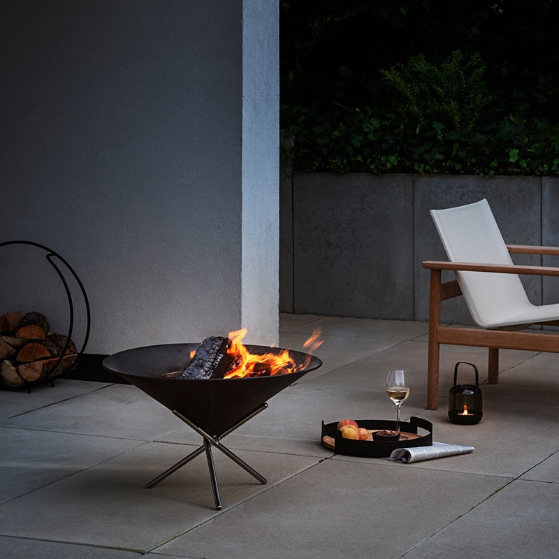 Outdoor patio with fire pit, chair, and wine glass on a dark evening.