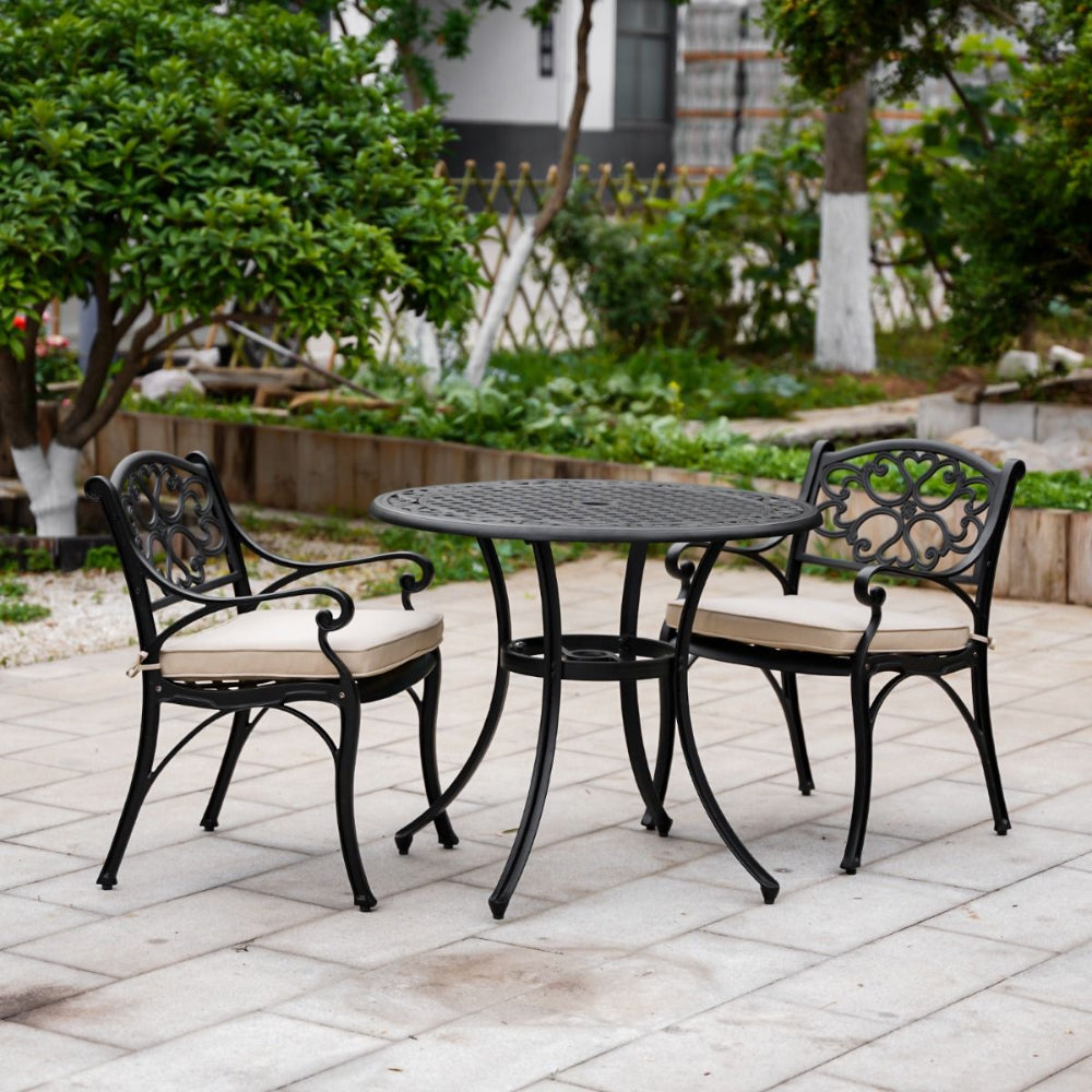 Outdoor patio set with black metal table and chairs on a stone patio.