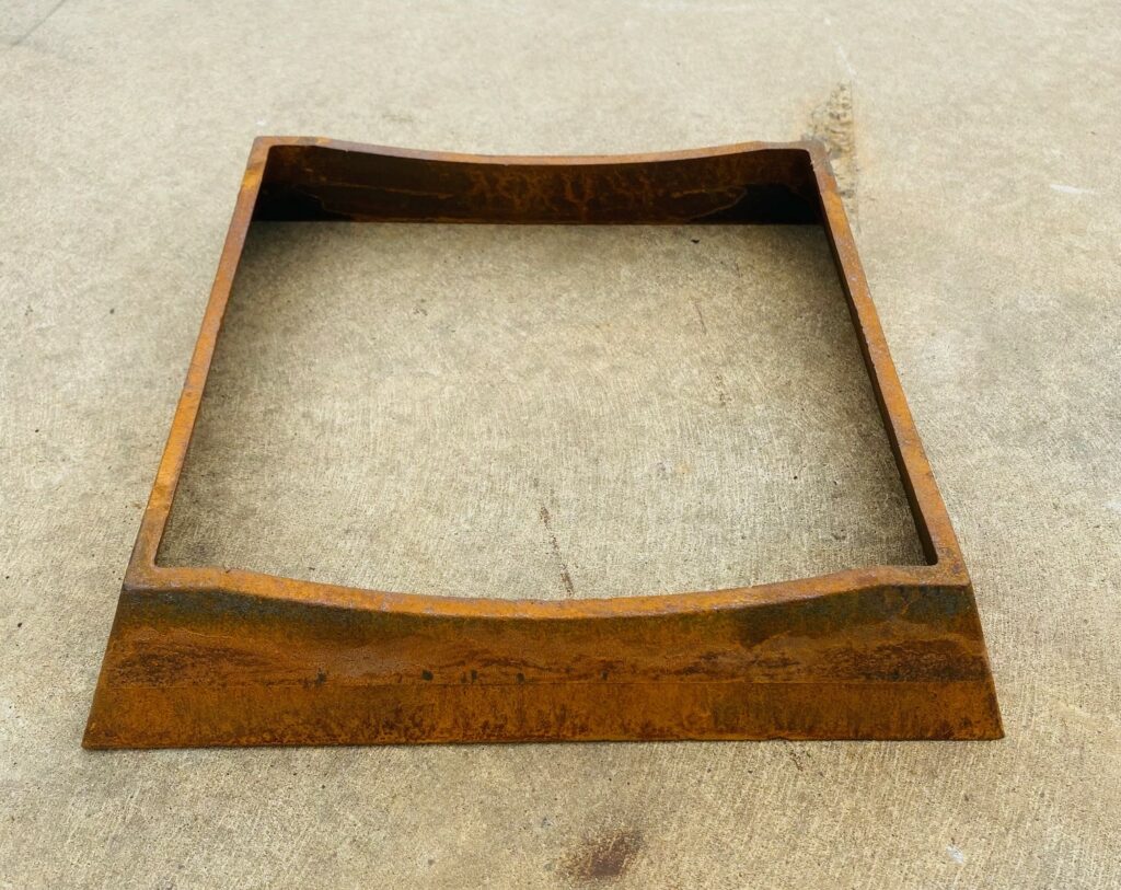 A square metal stand of the large metal fire pit on its own on a cement floor