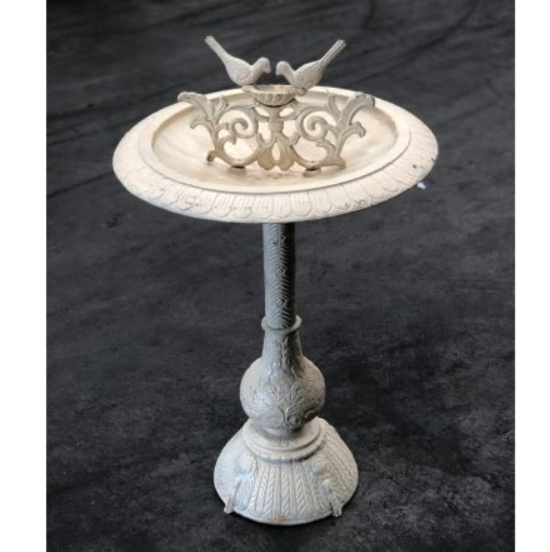 Two Birds Cast Iron Bird Bath in Antique White on a cement floored area.
