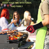Person grilling outdoors with friends in the background, wearing a green apron and red gloves.