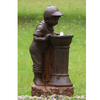 Boy at Water Fountain in garden setting with pebbles, and green grass with dandelions surrounding it.