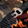 Metal bottle opener on a grill with flames in the background