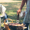 Person grilling food outdoors with a blurred background