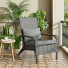 Gray armchair with cushions on a patterned floor with plants in the background