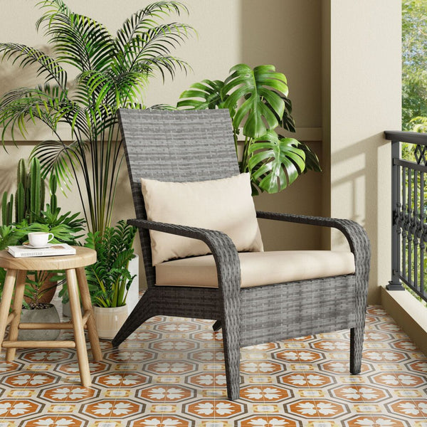 Gray wicker chair with beige cushion on a balcony with plants and a small table.