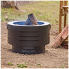Black fire pit with a log on a sandy ground