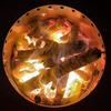 Top view looking down into a stainless steel fire pit with wood and fire burning on a black background.