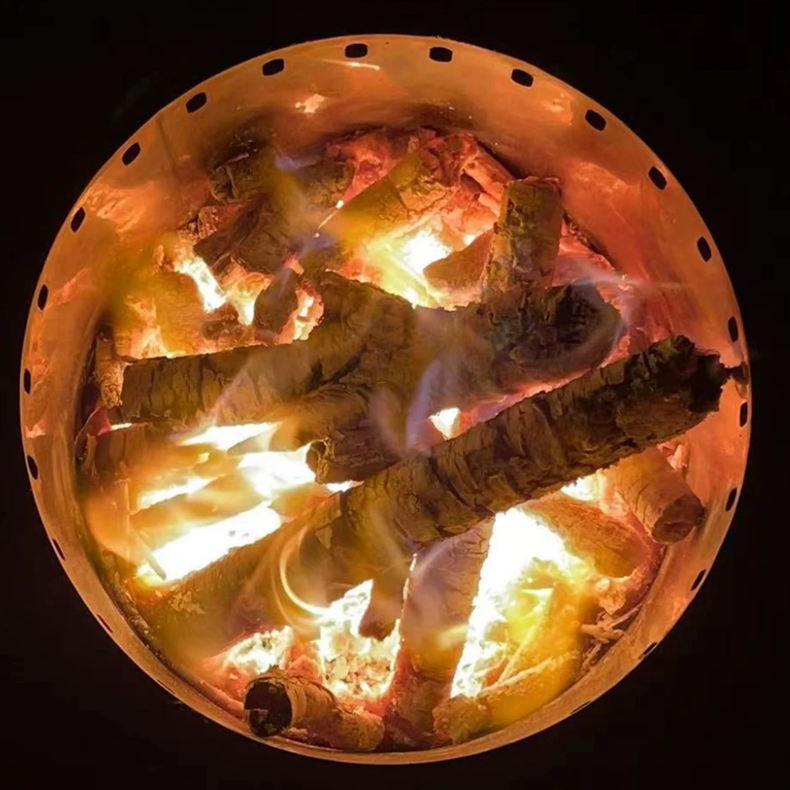 Top view looking down into a stainless steel fire pit with wood and fire burning on a black background.