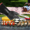 Person grilling skewered vegetables and sausages with a picnic setup in the background.