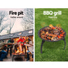 2-way split image of a portable black fire pit with a foldable design, one with a group of people gathered around a blazing fire and having cheers with their beers and wines, the other picture is of the same firepit grilling steak, sausages, kebabs and tomatoes, set on a grass area.