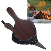 A dark wood and black studded fire tool with a pointed metal tip is shown on a white background, with a small inset photo of the tool being used over a campfire outdoors.