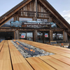 Galio Gas Fire Pit Insert Linear Automatic with fire burning in middle of a large wooden table at Humno restaurant which is an A-frame building that can be seen behind the fireplace.