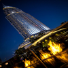 Galio Gas Fire Pit Insert Linear Automatic with fire burning at nighttime at a poolside and upwards view of a really tall highrise building in the background.