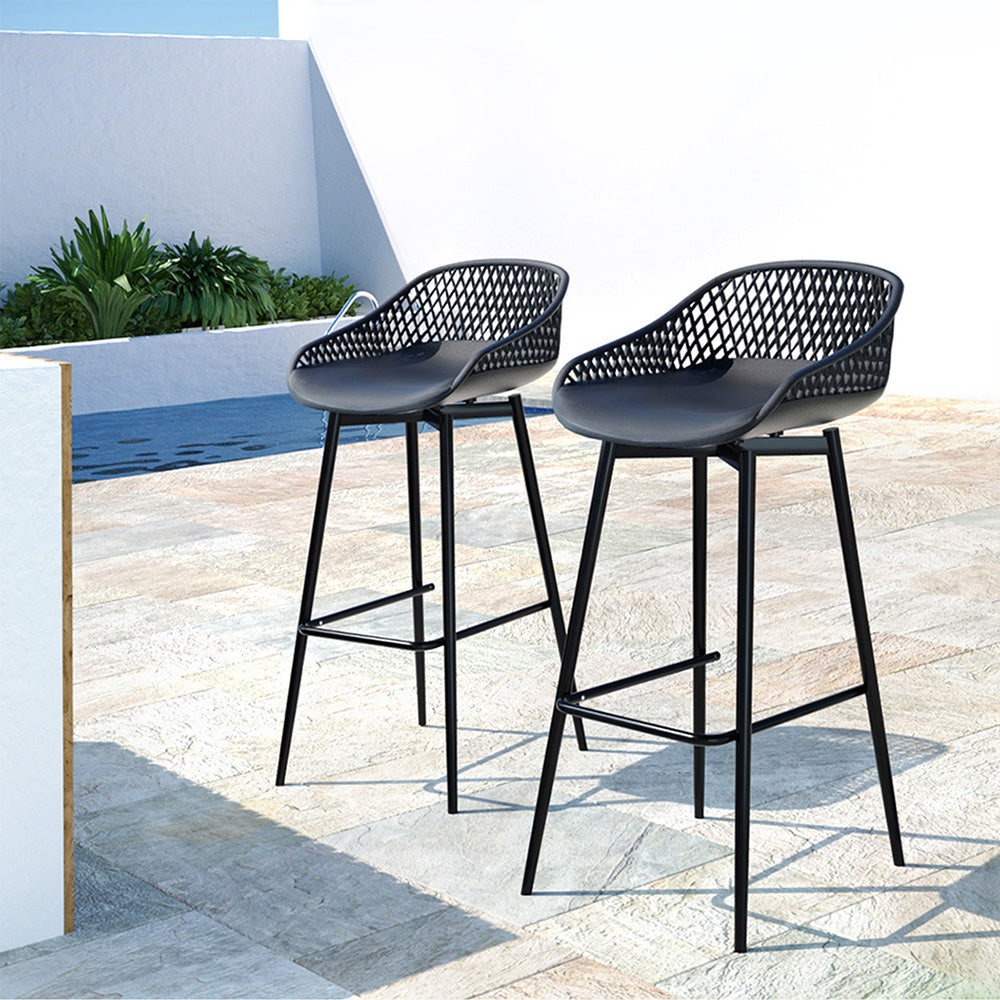 A pair of black Gardeon outdoor bar stools with plastic seats and metal frames, next to each other on a tiled surface in an outdoor poolside setting.