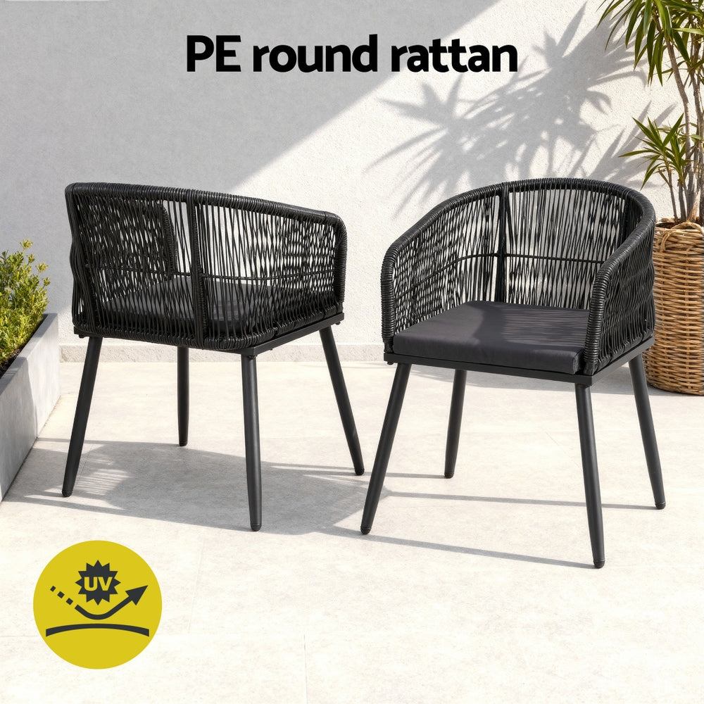 Two black PE round rattan chairs on a light surface with a plant in the background.
