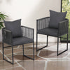 Two black metal chairs with gray cushions on a stone patio.