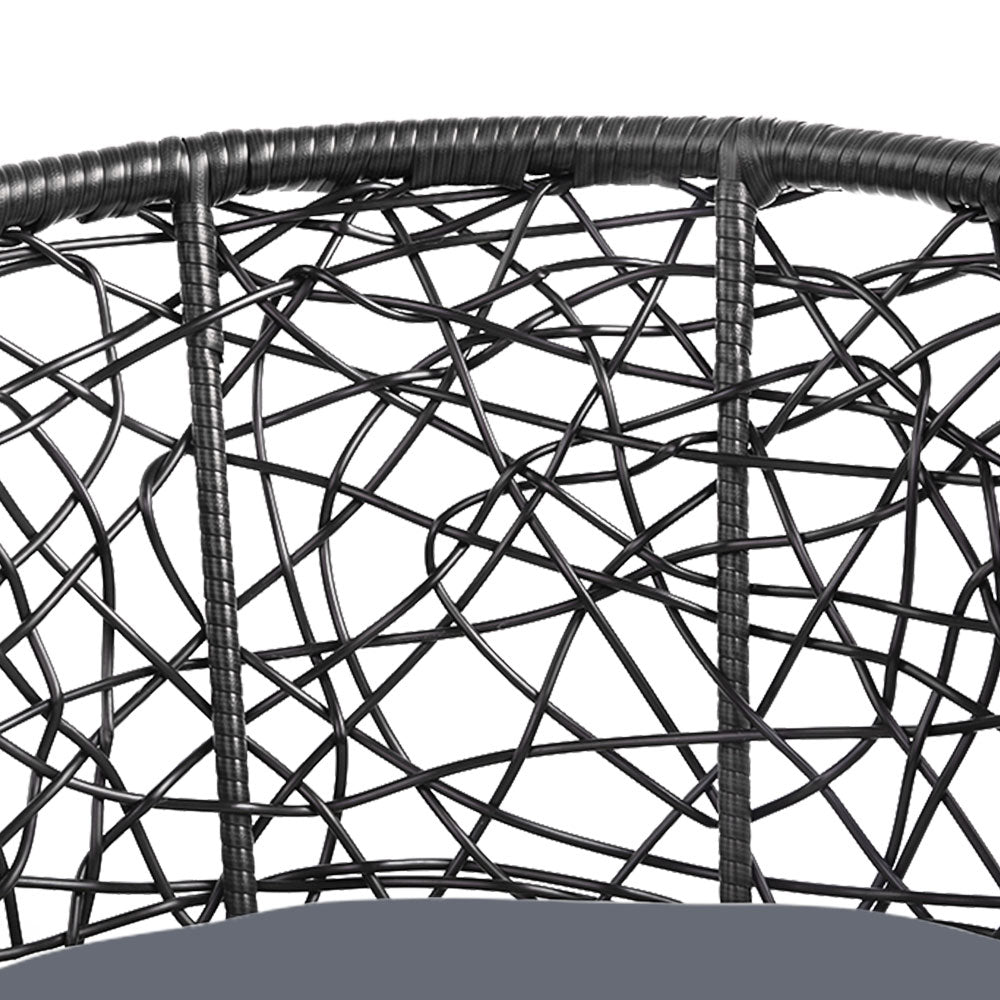 Close-up image of a black high-backed rattan chair showing its back design and weave and set against a white background.