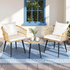 Two wicker chairs with white cushions and a matching table on a blue rug.