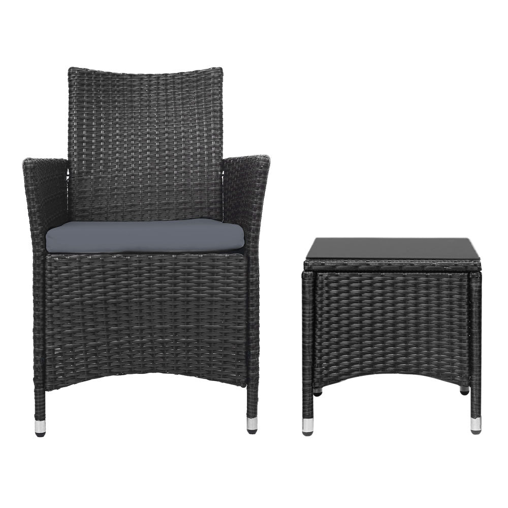 A black wicker chair with cushion and a matching black wicker side table with a glass top, on a white background.