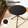Black round table with three legs on a wooden deck