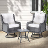 A 3-piece outdoor furniture set featuring a table and two chairs with grey weave pattern and white cushions, in an outdoor patio setting on wood decking with beige colour floor rug set in front of a wall and window with a plant to the side.