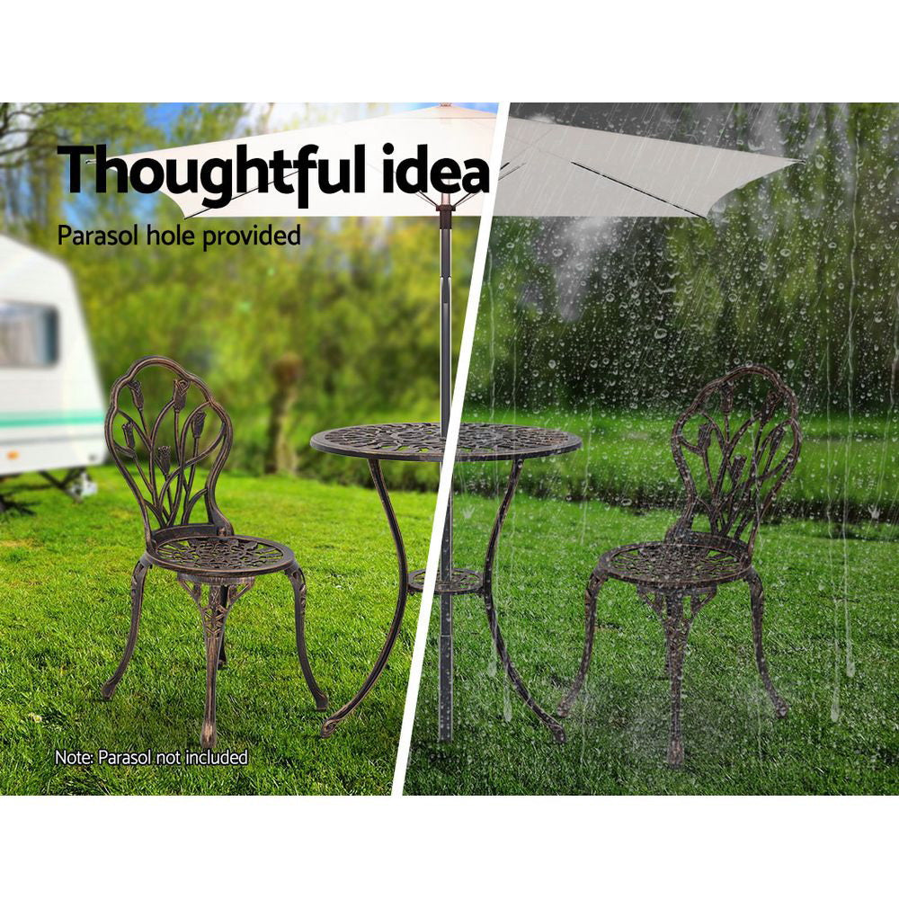 A bronze Gardeon bistro set including two chairs and a round table, made of cast aluminum with tulip designs, set on a grass and trees in the backdrop. The image is split into two showcasing the parasol hole holding a parasol in the middle of the table, half image in the sunshine offering shade and the other half in the rain also offering cover.