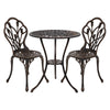 A bronze Gardeon 3-piece outdoor bistro set, including a round table and two chairs with a tulip floral pattern on the frame, made of cast aluminum, and set on a white background.
