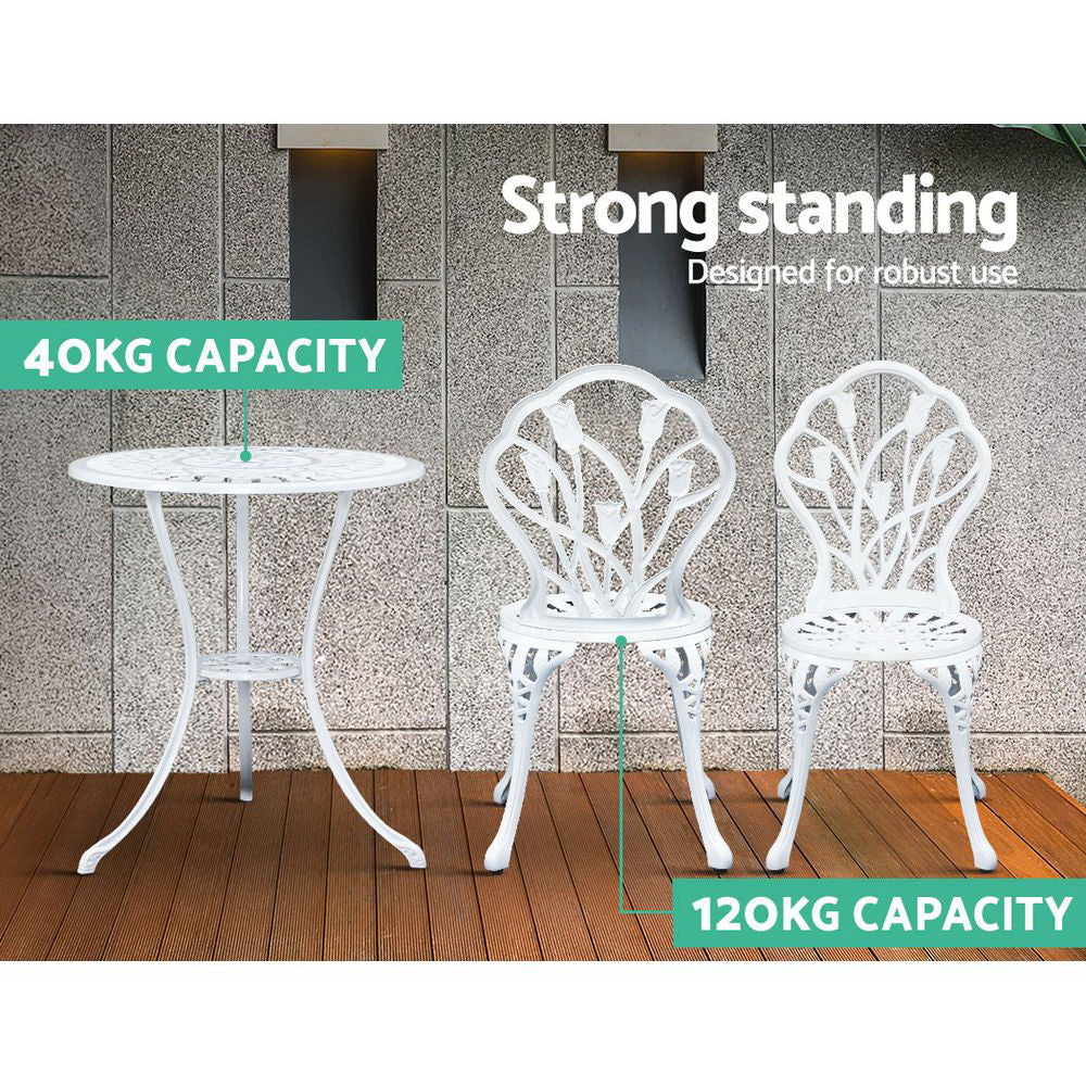 A white Gardeon bistro set including two chairs and a round table, made of cast aluminum with tulip patterns, set on a laminated wood floor before a grey tiled wall, one chair facing forward and one facing backwards, shows the weight capacity being 40kg for the table and 120kg for the chairs.