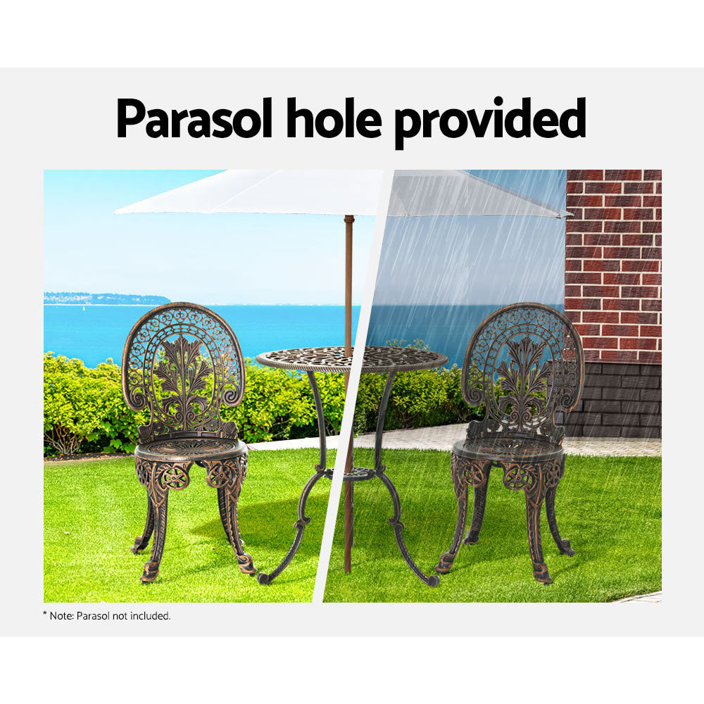 A bronze Gardeon bistro set including two chairs and a round table, made of cast aluminum with inticate designs, set on a grass with hedging and an ocean view in the backdrop. The image is split into two showcasing the parasol hole holding a parasol in the middle of the table, half image in the sunshine offering shade and the other half in the rain also offering cover.