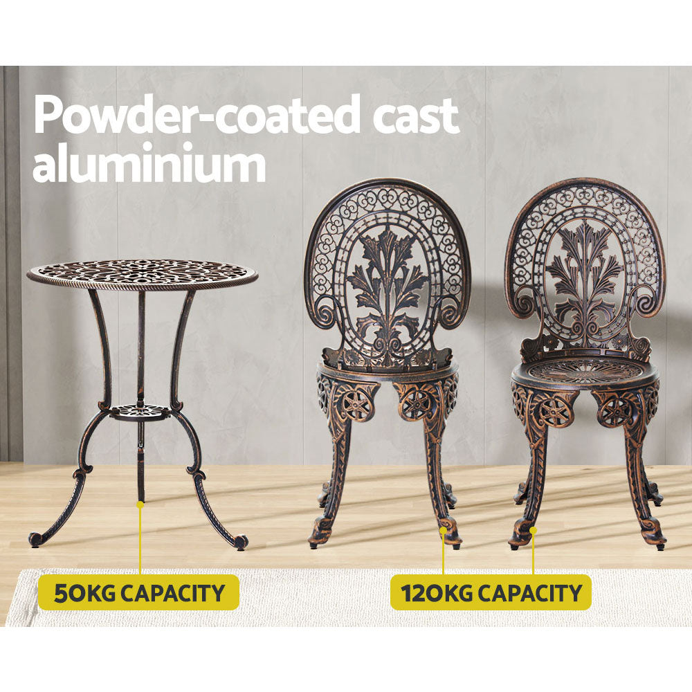 Bronze colour Gardeon bistro set including two chairs and a round table, made of cast aluminum with intricate patterns, set on a laminate floor before a grey wall, one chair facing forward and one facing backwards, shows the weight capacity being 50kg for the table and 120kg for the chairs.