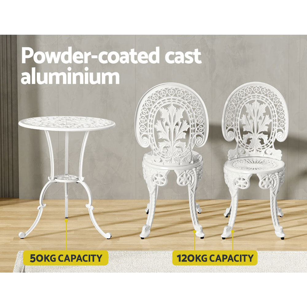 A white Gardeon bistro set including two chairs and a round table, made of cast aluminum with intricate patterns, set on a laminate floor before a grey wall, one chair facing forward and one facing backwards, shows the weight capacity being 50kg for the table and 120kg for the chairs.