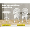 A white Gardeon bistro set including two chairs and a round table, made of cast aluminum with intricate patterns, set on a laminate floor before a grey wall, one chair facing forward and one facing backwards, shows the weight capacity being 50kg for the table and 120kg for the chairs.